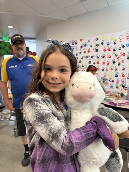 A girl hugging a plushy cow toy.